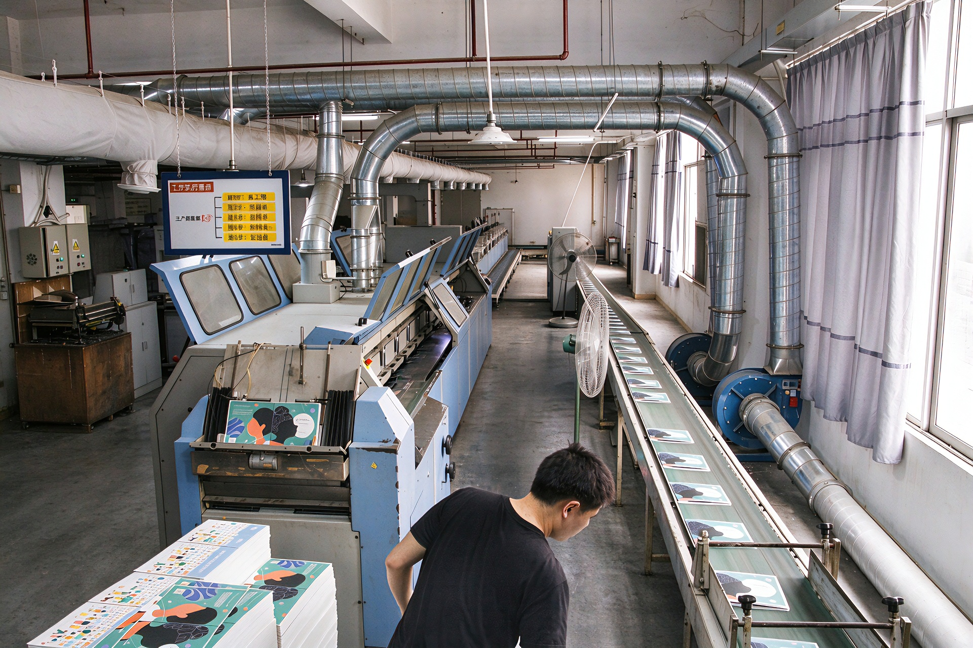 Worker monitoring notebook binding conveyor line in printing factory, custom journal production