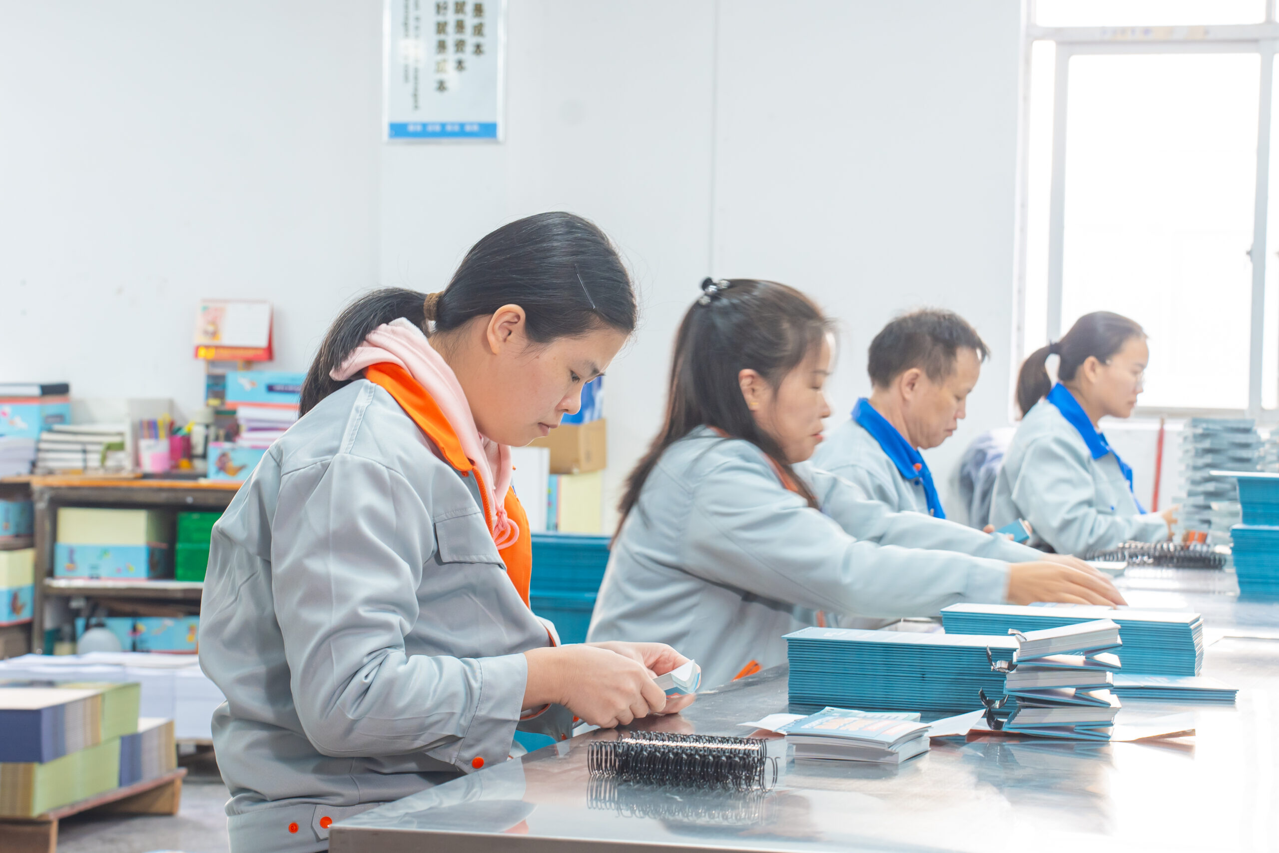 Factory workers binding custom calendars in print workshop