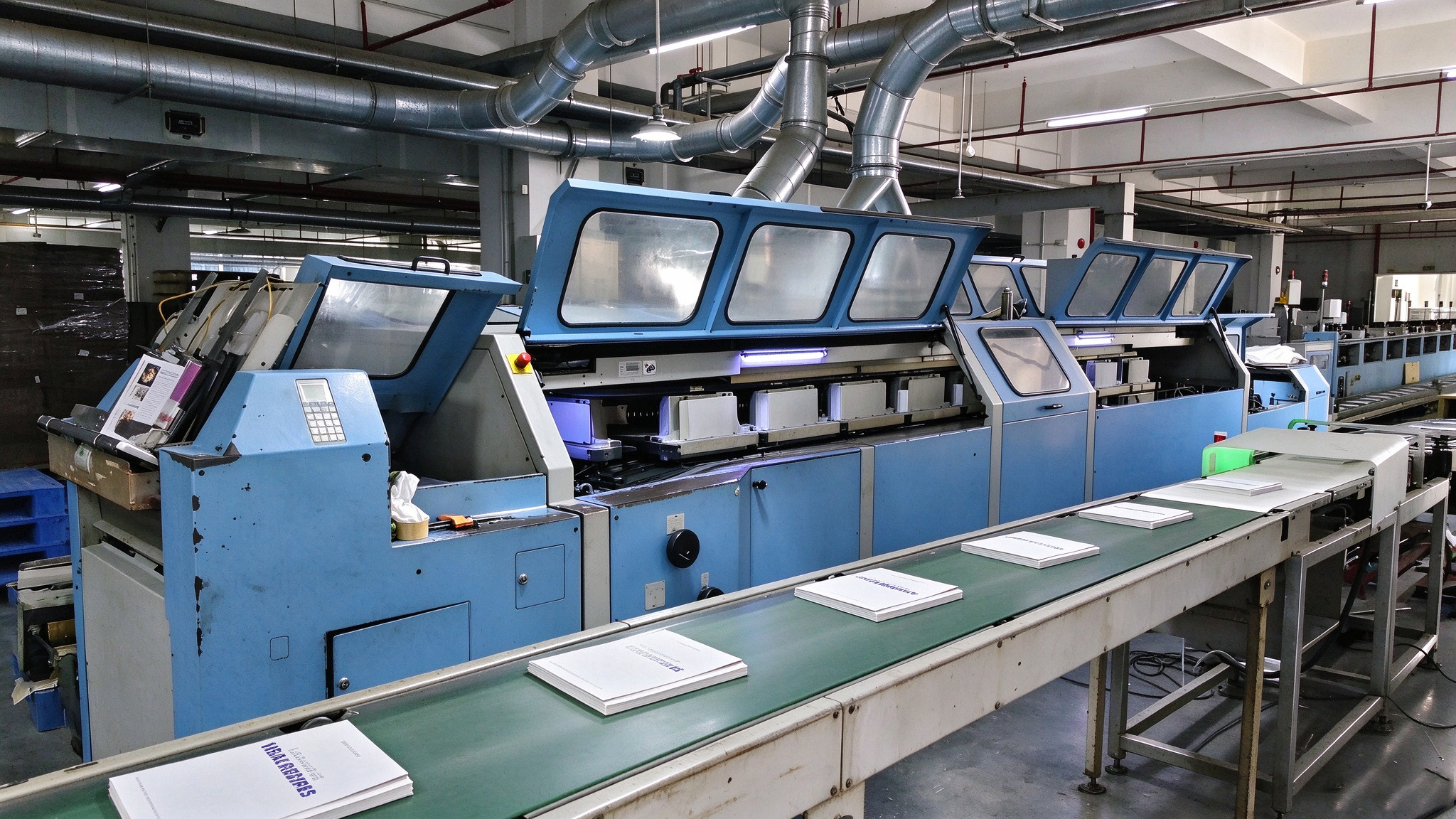 Swiss Müller Martini automatic perfect binding line for high-volume paperback production, with inline spine milling, gluing, cover feeding and continuous book output.